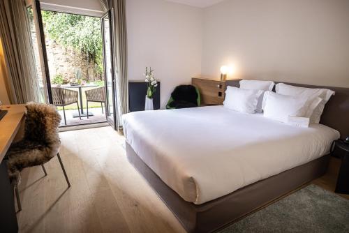 a bedroom with a large white bed and a balcony at Relais et Châteaux Le Chambard in Kaysersberg