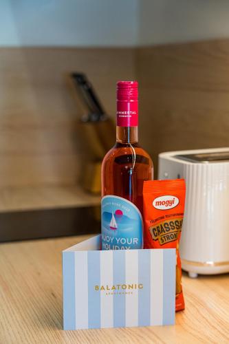 a bottle of alcohol and a box of food at Balatonic Lime apartmanház in Siófok