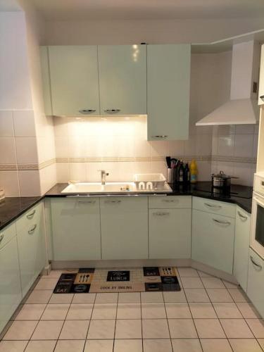 une cuisine avec des armoires blanches et un évier dans l'établissement Cosy flat in Beauvais city center, à Beauvais
