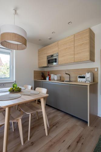 a kitchen with wooden cabinets and a table with chairs at Balatonic Lime apartmanház in Siófok