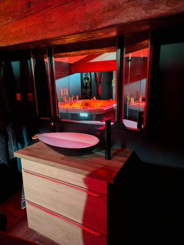 La salle de bains est pourvue d'un lavabo rouge et d'un miroir. dans l'établissement La parenthèse Love room, à Moussan