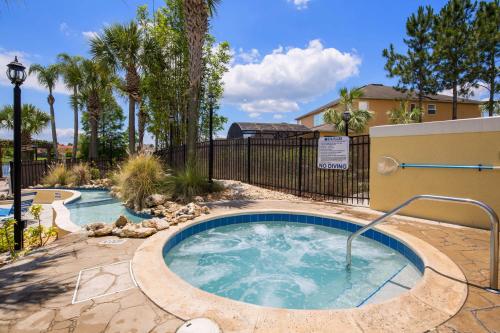 a hot tub in a yard with a fence and trees at Walkin' on Sunshine - 5 bed pool home in Terra Verde Resort near Disney in Kissimmee