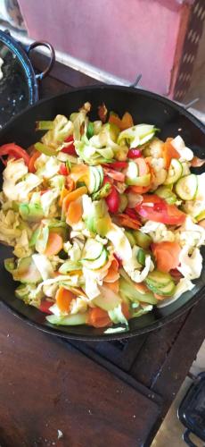 a pan filled with a salad of vegetables on a table at Sitio Alecrim Gastronomia e Hospedaria in Alagoa