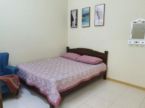 Un dormitorio con una cama y una silla azul. en Teratak Ayuni with Private pool, en Batu Gajah