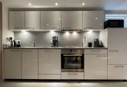 ヴォルフスブルクにあるLightplace - Boxspring - Parkplatz- Nähe City und VWの白いキャビネットとオーブン付きのキッチン
