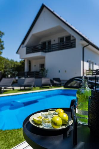 a plate of fruit on a table next to a swimming pool at Balatonic Lime apartmanház in Siófok