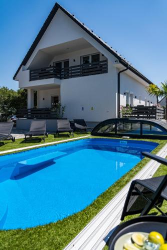a villa with a swimming pool and a house at Balatonic Lime apartmanház in Siófok