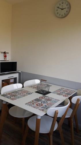 une table à manger avec des chaises et une horloge murale dans l'établissement T2 proche gare avec WiFi parking, à Angers