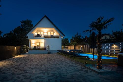 a villa with a swimming pool at night at Balatonic Lime apartmanház in Siófok