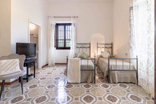 a bedroom with two beds and a desk and a television at Il Castello degli Ulivi-Agriturismo in natura in Roccella Ionica