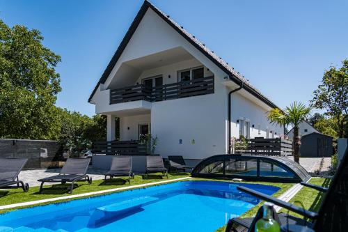 a villa with a swimming pool and a house at Balatonic Lime apartmanház in Siófok