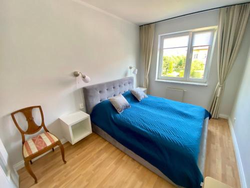 a bedroom with a blue bed and a chair at Apartament Horeszków by Prestige Home in Szczecin