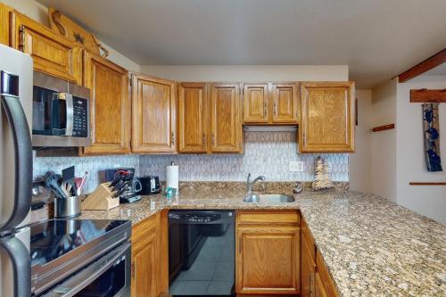 a kitchen with wooden cabinets and a black dishwasher at Buffalo Village 402 in Silverthorne