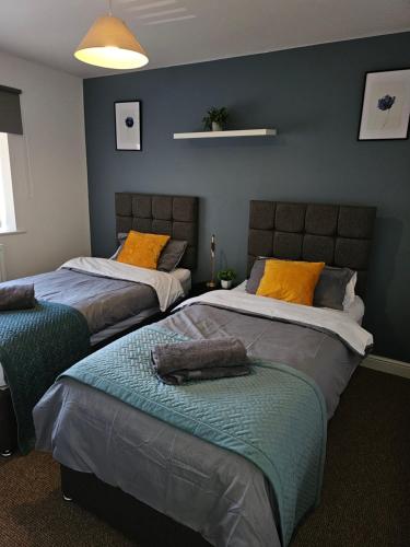 two beds in a room with blue walls at Sotys Contractors, Long and Short term stays in Derby