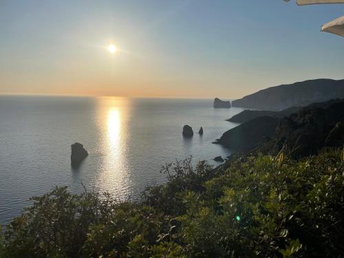 a sunset over the ocean with rocks in the water at Casa vacanze i Giardini Iglesias in Iglesias