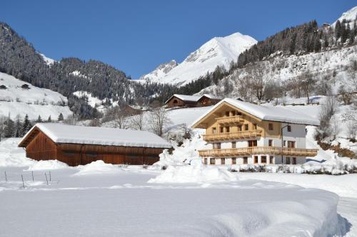 a large building in the snow with mountains in the background at Apartment Santnerhof in Virgen
