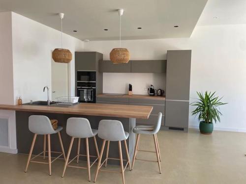 - une cuisine avec un comptoir en bois et des tabourets blancs dans l'établissement Villa Saint Quentin La Poterie, à Saint-Quentin-la-Poterie