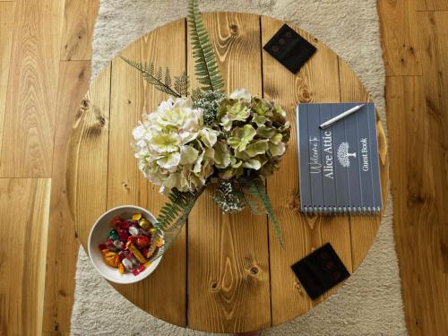 a wooden table with a bowl of flowers and a book at Studio-King Bed-Wye Valley Views in Trostrey