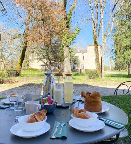 une table garnie de assiettes de viennoiseries et de pain dans l'établissement L'Appartement de l'Orangerie, à Lempaut