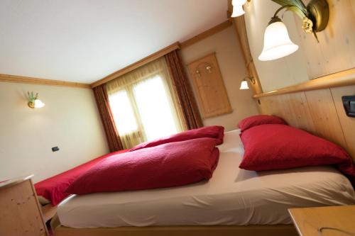 a bedroom with red pillows on a bed with a window at Hotel Champagne in Livigno