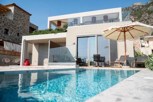 a house with a swimming pool and an umbrella at Petradi Suites in Kalamata