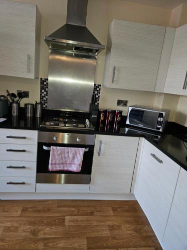 a kitchen with white cabinets and a stove top oven at Sotys Contractors, Long and Short term stays in Derby