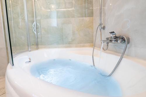 a bath tub with a shower with blue water at Petradi Suites in Kalamata
