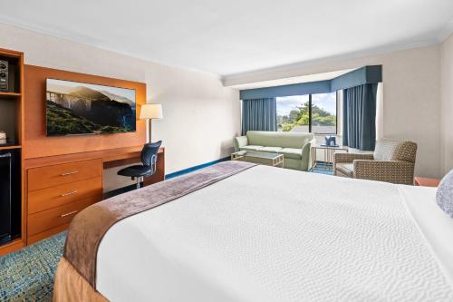 a hotel room with a large bed and a living room at Best Western De Anza Inn in Monterey