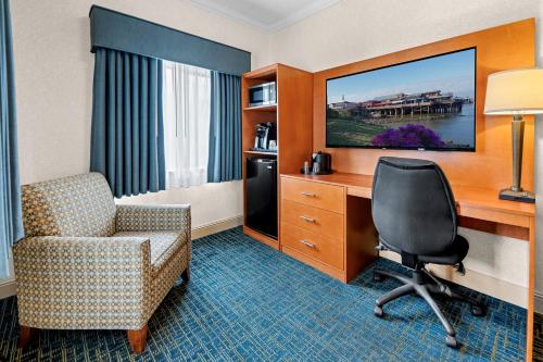 a hotel room with a chair and a desk and a television at Best Western De Anza Inn in Monterey