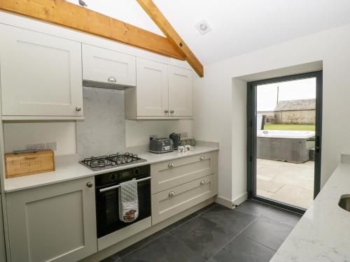 a kitchen with white cabinets and a stove top oven at The Byre in Bridgend