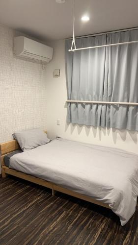 a bedroom with a bed with a curtain on it at 民泊TOKYO one シェアハウス in Tokyo
