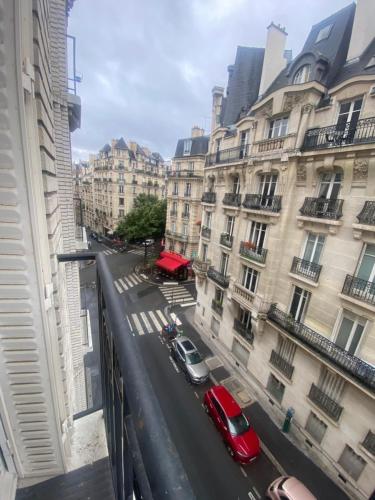 - une vue sur une rue de la ville avec des bâtiments et une voiture rouge dans l'établissement AG Immobilier 75, à Paris