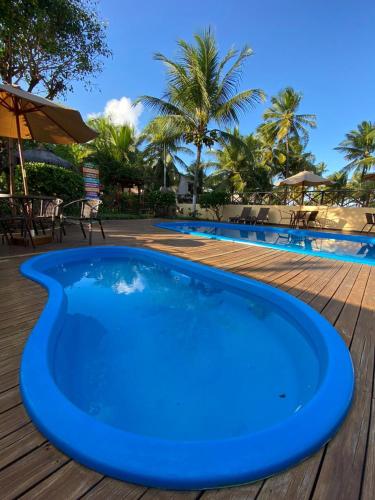 a blue swimming pool next to a wooden deck at Pousada Oceano Atlântico in Marau