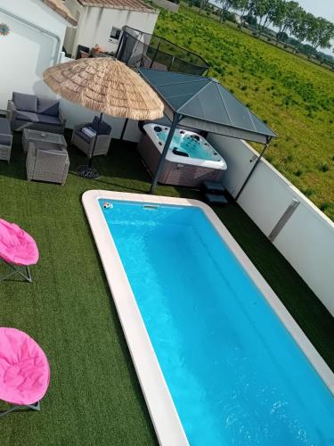 - une piscine avec un parasol, des chaises et une table dans l'établissement Les plaisirs de camargues, à Aimargues
