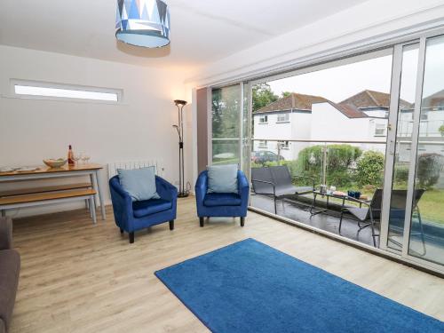 a living room with two blue chairs and a table at 28 Coedrath Park in Saundersfoot