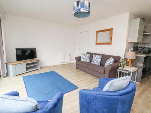 a living room with two blue chairs and a couch at 28 Coedrath Park in Saundersfoot