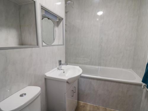 a bathroom with a sink and a toilet and a tub at 28 Coedrath Park in Saundersfoot