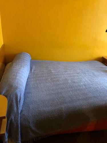 a blue bed in a room with a yellow wall at Hotel Villa Plaisance in Lourdes