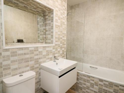 a bathroom with a toilet and a sink and a mirror at 36 Coedrath Park in Saundersfoot
