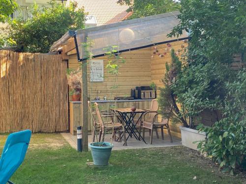 a patio with a table and chairs in a backyard at Cabane suspendue dans les arbres in Villebon-sur-Yvette