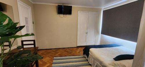 a bedroom with a bed and a tv on the wall at hostal andino in Santiago