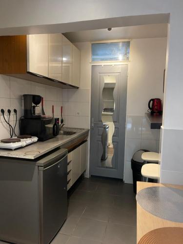 La cuisine est équipée de placards blancs et d'un réfrigérateur gris. dans l'établissement Petit appartement idéal pour deux personnes, offrant une belle vue sur jardin, proche des commodités et à moins de 30 minutes de Paris en transport, à Chennevières-sur-Marne