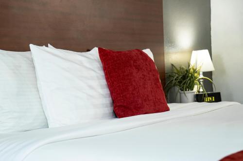 a red pillow sitting on a bed with white pillows at Victorian Inn & Suites-York in York