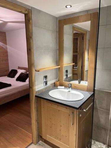une salle de bain avec un lavabo et un lit dans l'établissement Valmorel Ski au pied avec Parking couvert !, à Valmorel