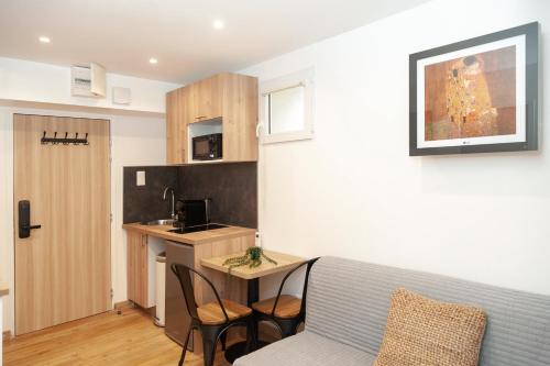 a living room with a couch and a table and a kitchen at Villa Des Bégonias - PSG in Le Pré-Saint-Gervais