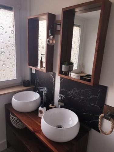une salle de bain avec deux lavabos et deux miroirs dans l'établissement Maison de vacances proche des plages, à Binic