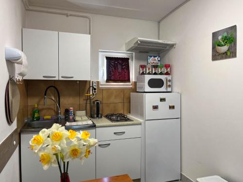 a kitchen with white cabinets and yellow flowers in a vase at Apartmani Moslavina, free big parking, workspace, crib, satin cotton sheets in Kutina