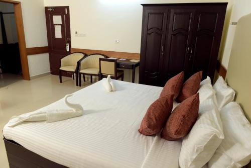 a bedroom with a bed with brown and white pillows at Paray Village County in Kollengode