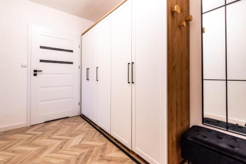 a walk in closet with white cabinets and wood floors at Feels like home Apartment - Olsztyn in Olsztyn