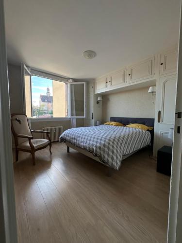 une chambre avec un lit, une chaise et une fenêtre dans l'établissement Charmant appartement en centre de Montluçon, à Montluçon